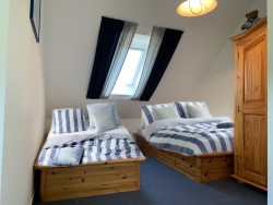 Foto: Ferienhaus Mien lüttje Huuske, Greetsiel:  Das zweite Schlafzimmer mit zwei Einzelbetten unter dem großen Dachfenster.